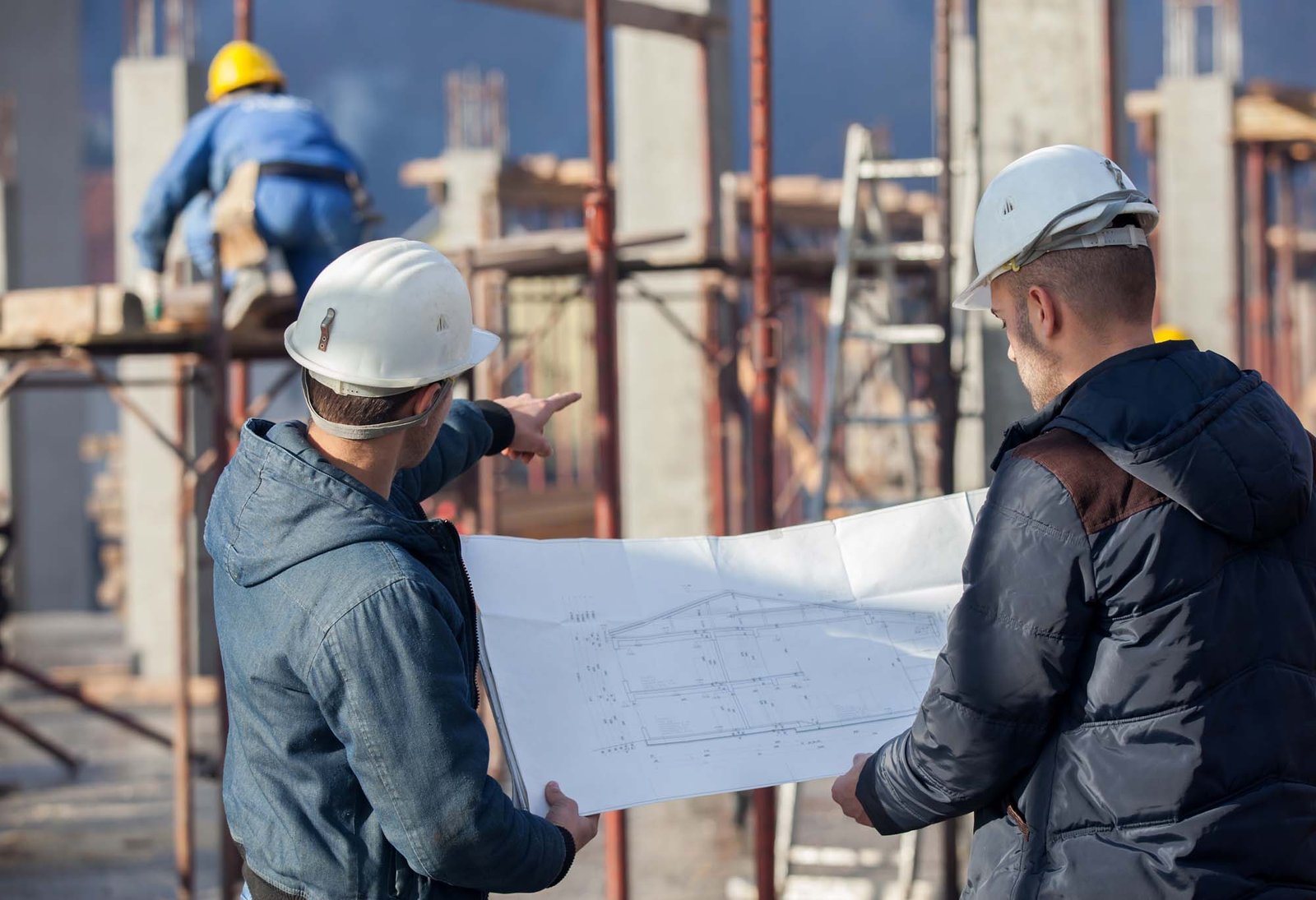 Construction workers reviewing blueprints at job site